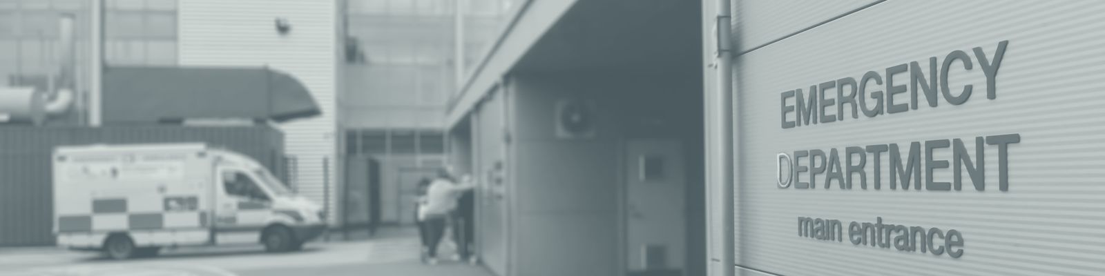 An ambulance and people outside the main entrance of a hospital emergency department